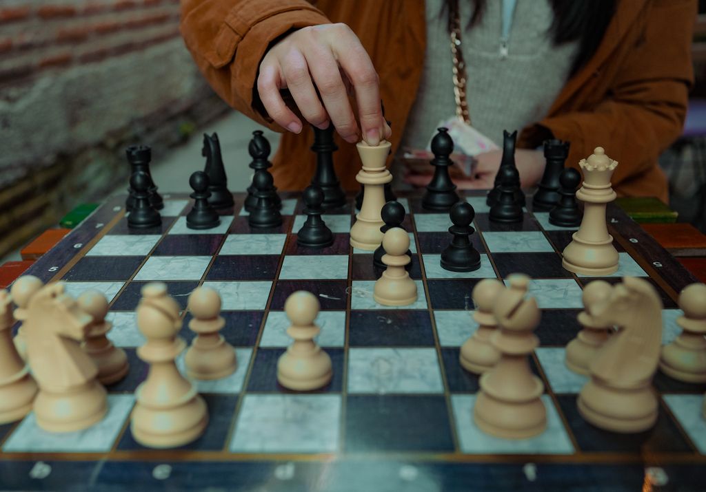 A person making a strategic move during a chess game, focusing on the pieces.